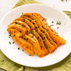 Grilled sliced sweet potatoes fanned out and garnished with herbs.