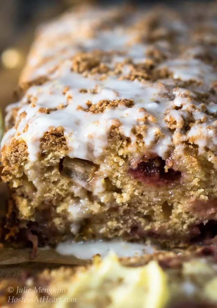 Table front view of the front of a sliced Strawberry Rhubarb Bread with Streusel top that\'s been drizzled with glaze.