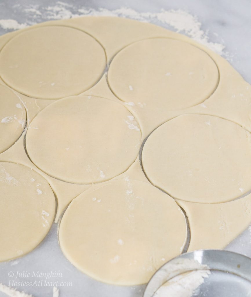 A rolled pie crust stamped with circles for blueberry pineapple hand pies.