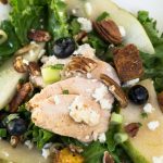top view of a green salad with slices of chicken, blueberries and pears