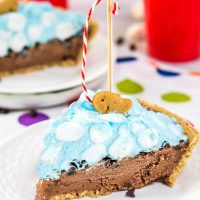 A slice of ice cream pie topped with blue-colored ice cream and marshmallows indicating it's water. A goldfish cookie with on the top with a crafted fishing pole. A second piece sits in the backgroud.