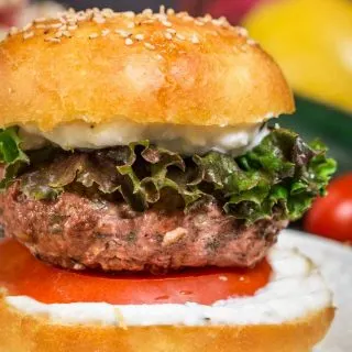 Close up of lamb burger between bun with tomato and sauce