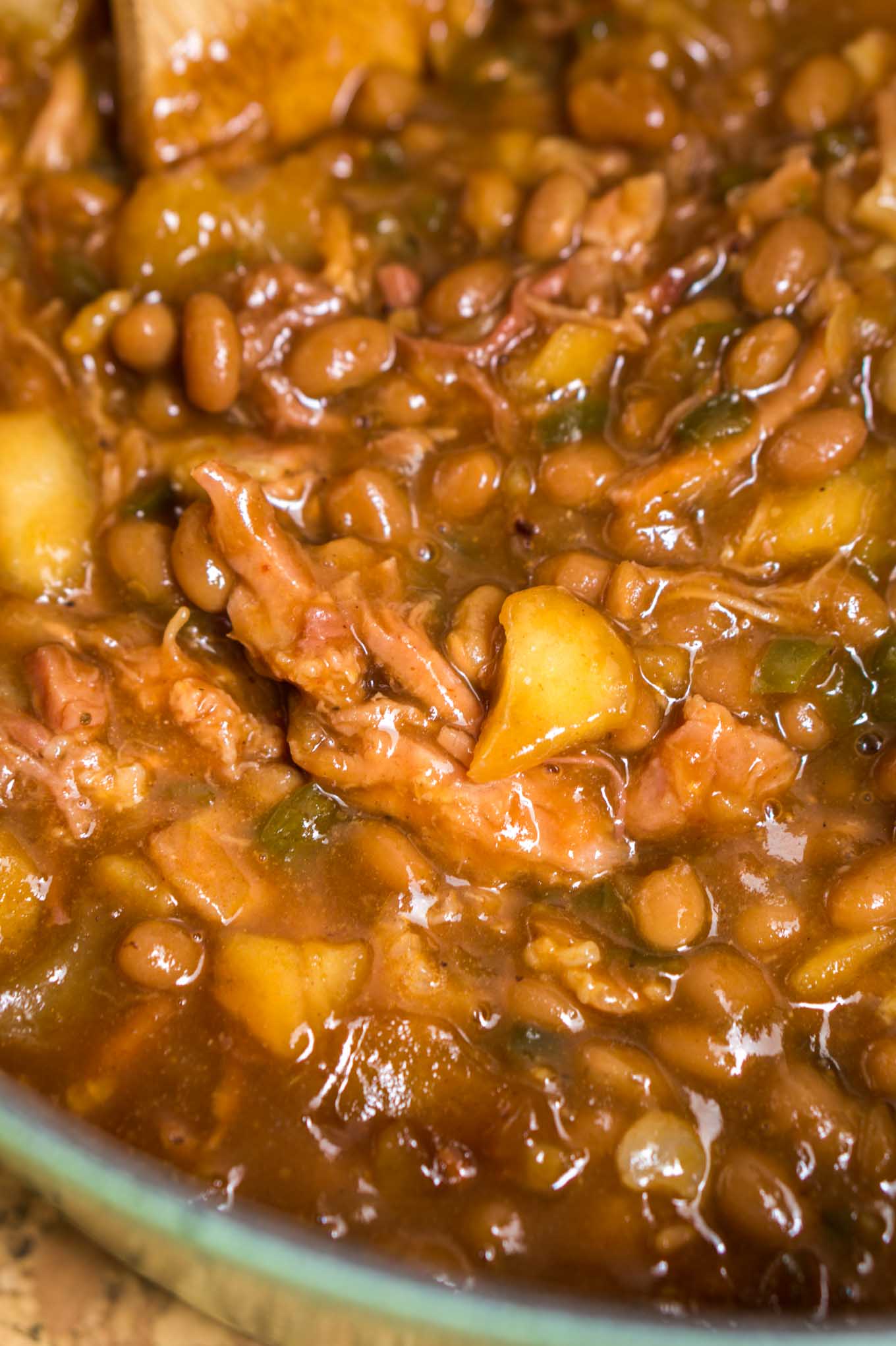 Close up of Apple Baked Beans in a cast iron dutch oven filled with apples, shredded pork and jalapenos.