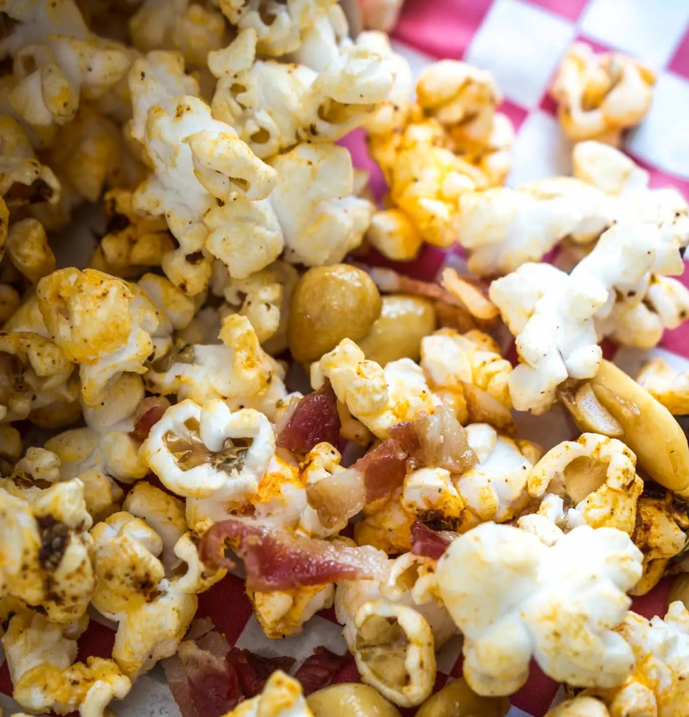 Close up of Honey Nut Popcorn with bacon on a red checked napkin.