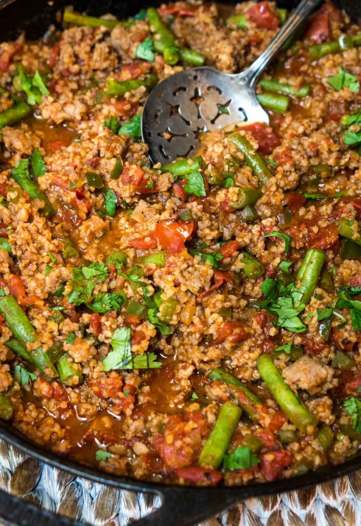 Close up of Sausage and Bulgur Wheat casserole with an antique spoon sitting in it.  