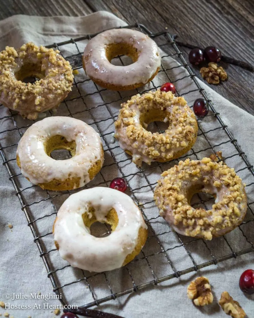 Cooling rack filled with iced donuts. Some topped with crushed nuts. - HostessAtHeart.com