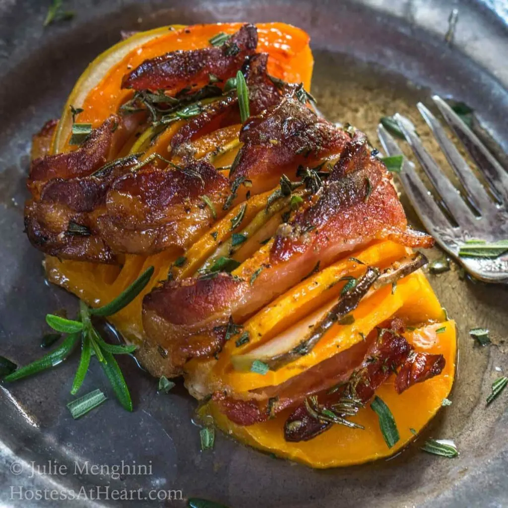 A butternut squash sliced with bacon interwoven topped with rosemary