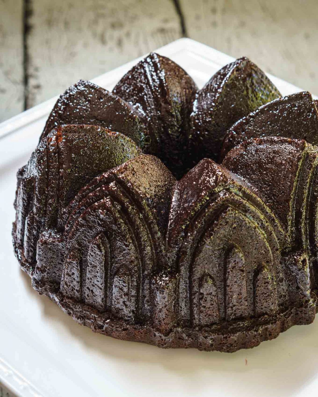 A top-angled view of a raspberry glazed chocolate raspberry bundt pan sitting on a white plate.