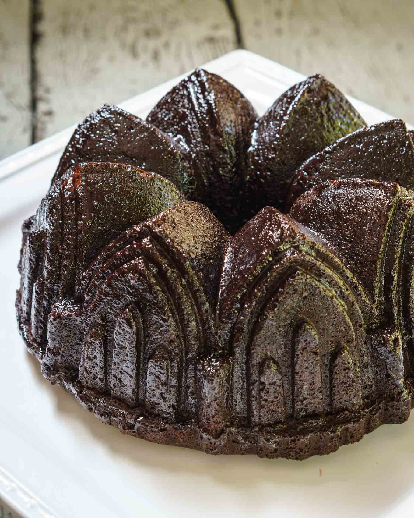 A top-angled view of a raspberry glazed chocolate raspberry bundt pan sitting on a white plate.