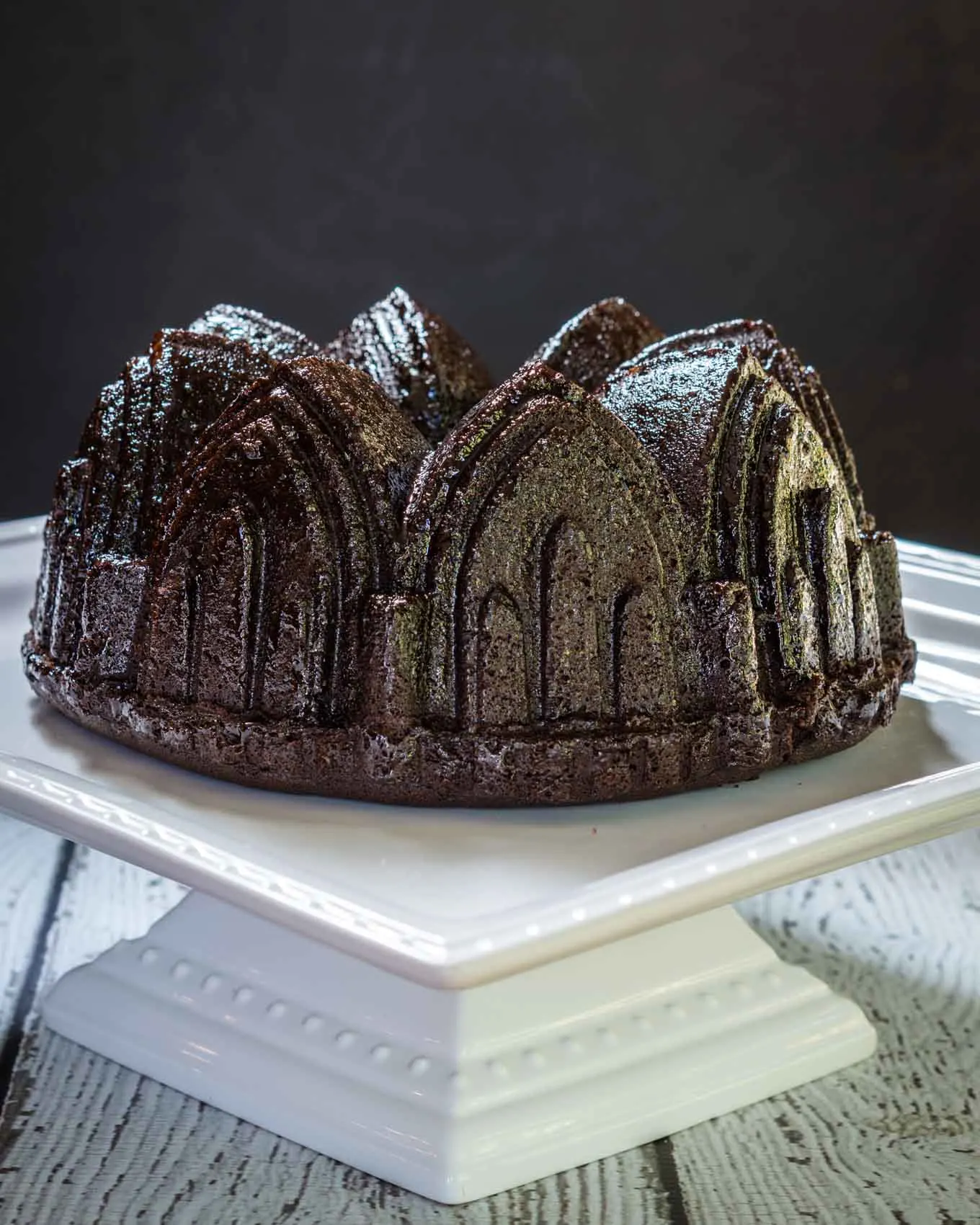 A top-angled view of a raspberry glazed chocolate raspberry bundt pan sitting on a white plate.