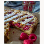 A front view of a raspberry linzer torte with a lattice shell, dusted with powdered sugar.