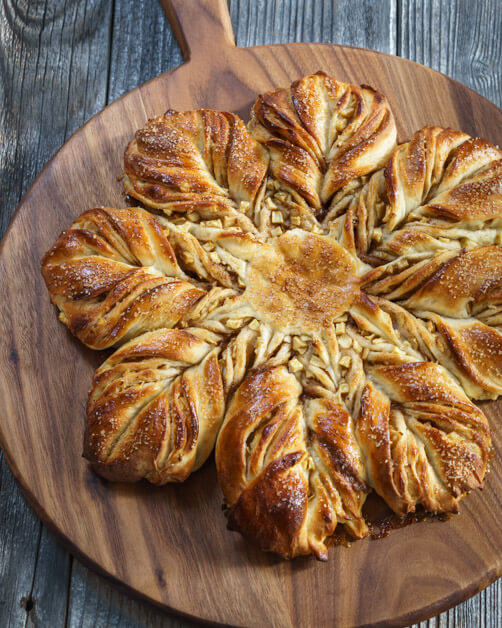 Top-down view of a star-shaped bread filled with diced bread that sits on a wood cutting board.