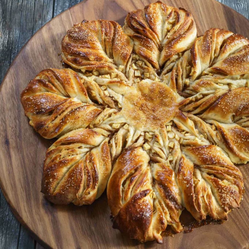 Top-down view of Spiced Apple Bread twisted to resemble a star sitting on a wooden cutting board.