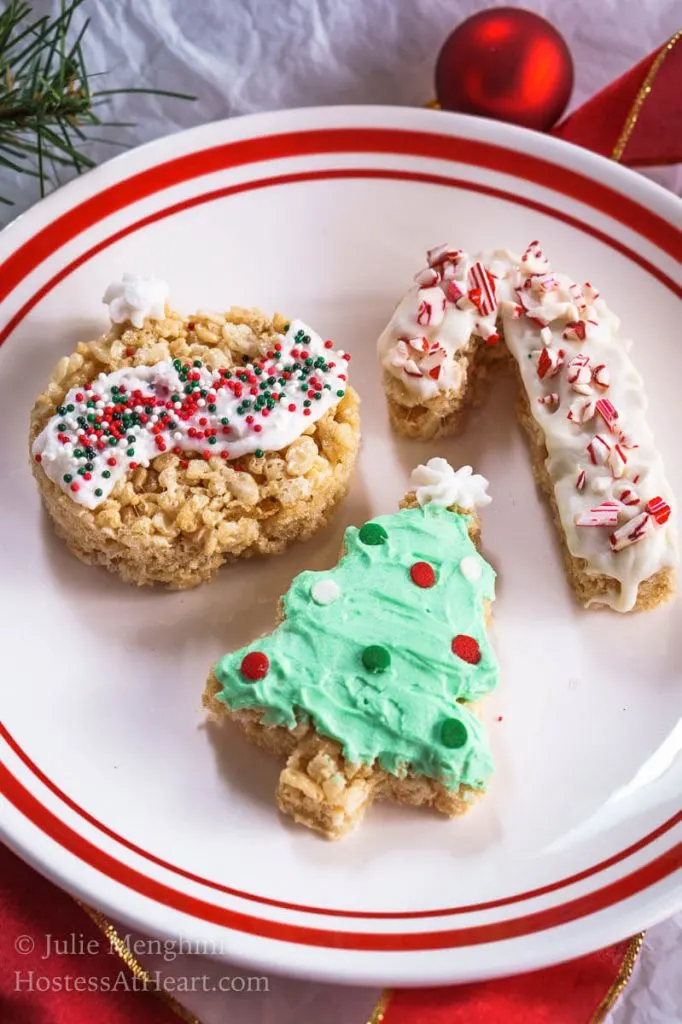 Three Chrismas cookies made out of Rice Krispie cookies that have been frosted and decorated with sprinkles.