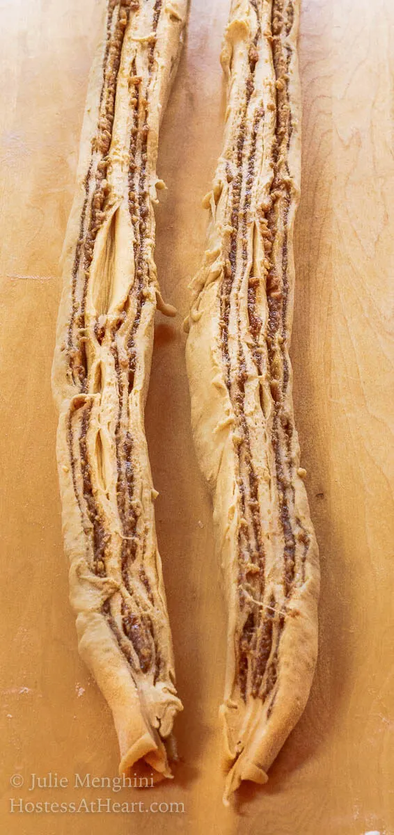 Two strips of sliced pieces of dough that have been filled with a cinnamon filling with the cut side up - Hostess At Heart