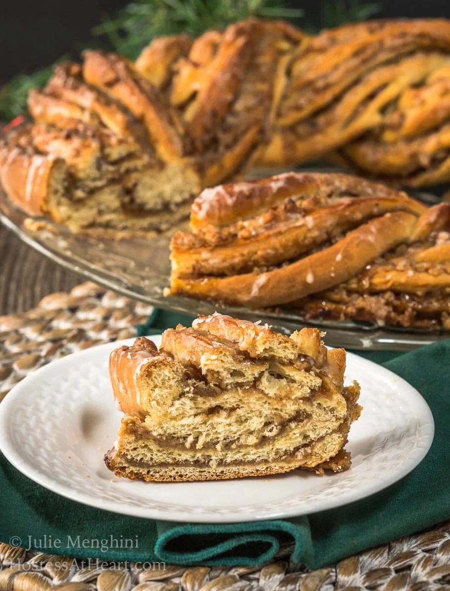 Sideview of a cut piece of cinnamon filled wreath bread topped with glaze - HostessAtHeart.com