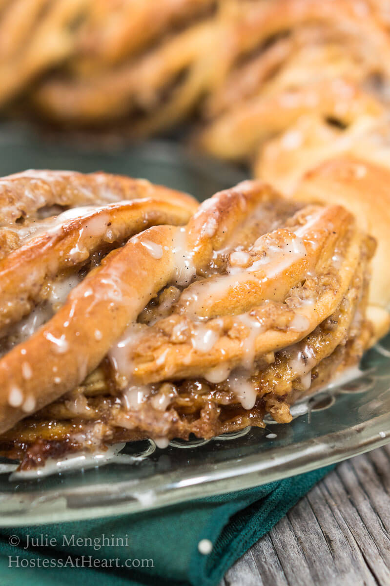 Close up side view of a twisted cinnamon bread roll wreath drizzled with glaze. HostessAtHeart.com