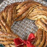 A bread wreath made filled with a cinnamon filling. Two Christmas bulbs sit in the background. Hostess At Heart