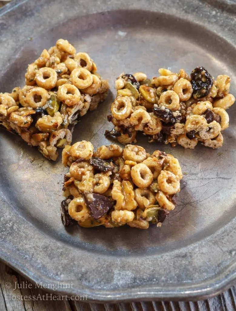 Three bars made from honey, whole-grain cereal, and chocolate chunks sitting on a metal plate