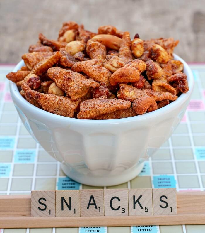 Corn nut snack in a white bowl over a scrabble board with tiles spelling out snacks.