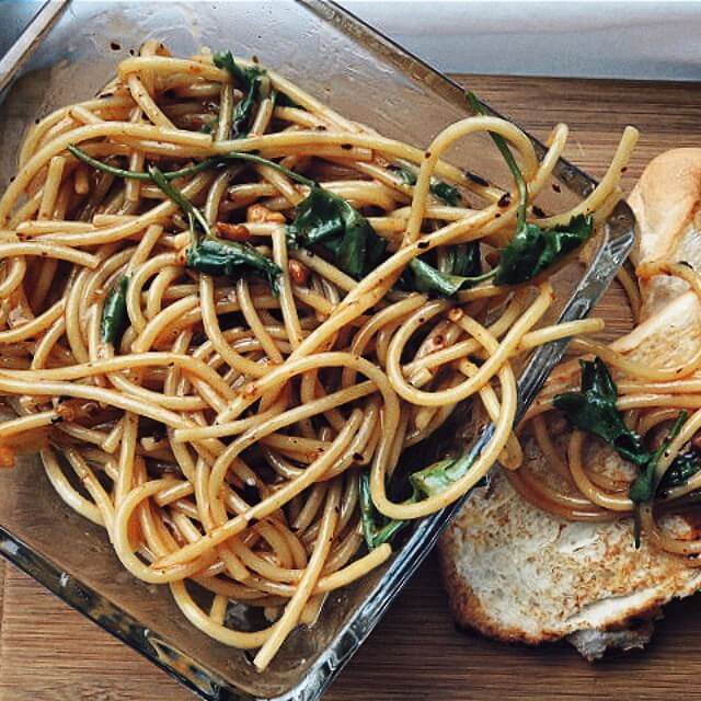 Sesame Peanut Noodles sitting on a glass plate over a wood board.