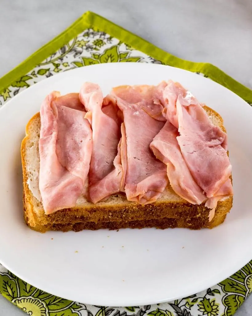 A Slice of bread layered with slices of ham.