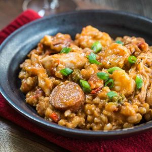 A bowl of Jambalaya made with Farro and garnished with green onion.