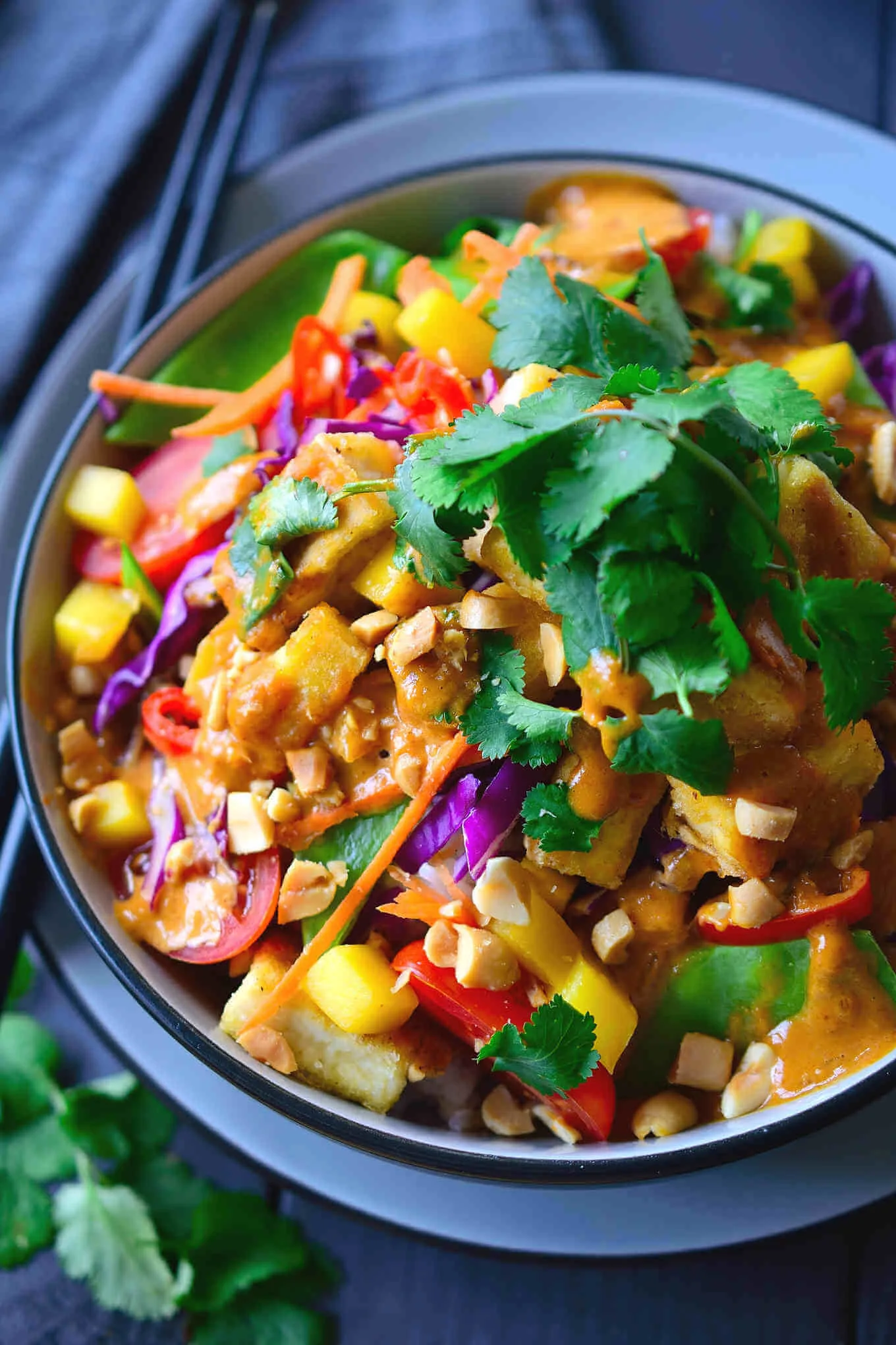 A colorful corn salad called a buddha bowl sitting in a blue bowl.
