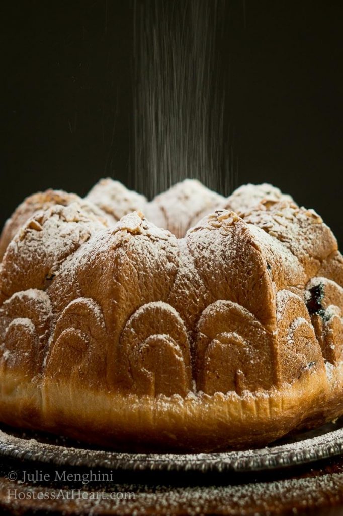 A close-up view of a Cherry Almond Kugelhopf with powdered sugar being sifted over the top.