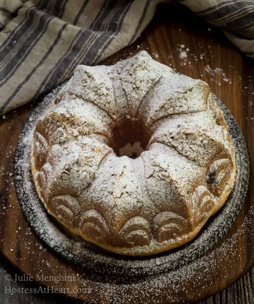 Top-down view of a Cherry Almond Kugelhopf dusted with powdered sugar sitting over a wooden cutting board.