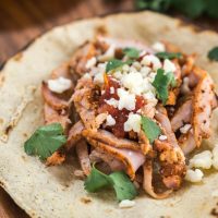 Taco and Al pastor garnished with Cotija cheese and cilantro.