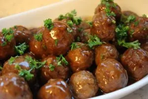 White bowl filled with meatballs that have been garnished with parsley.