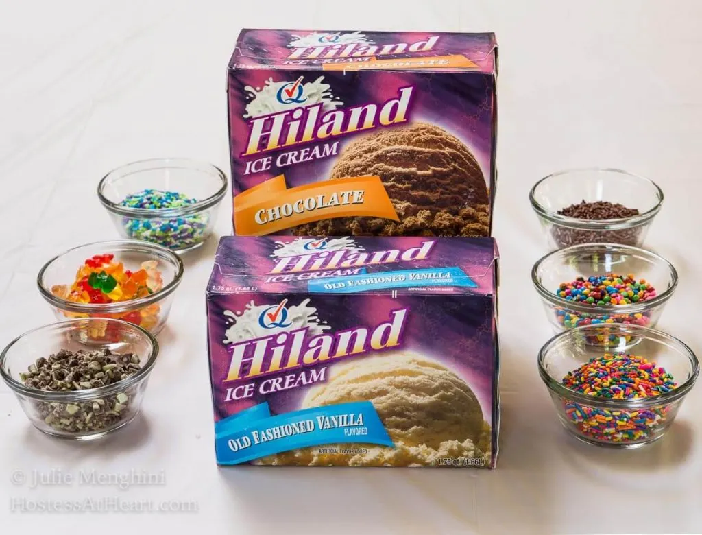 Two containers of Highland Ice Cream with dishes of multiple colored sprinkles for making Ice Cream Pops.