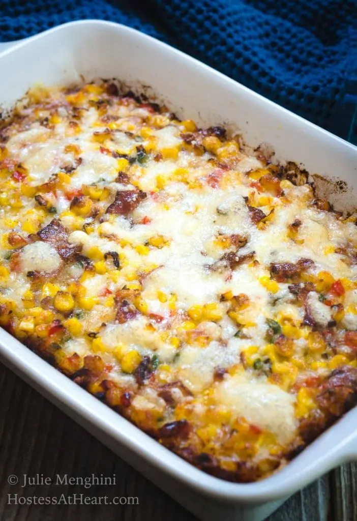 A white casserole dish of roasted corn and bacon,