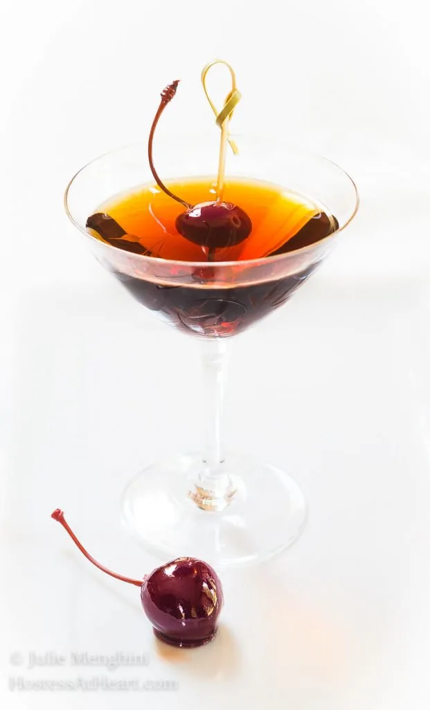  Cuban Manhattan Cocktail in a martini glass with a shiny skewered bing cherry.