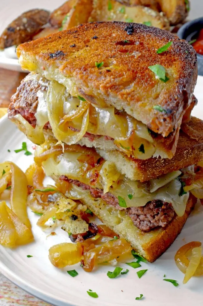 Stack of slices of a Patty Melt Sandwich on toasted bread showing the beef and onion ingredients.