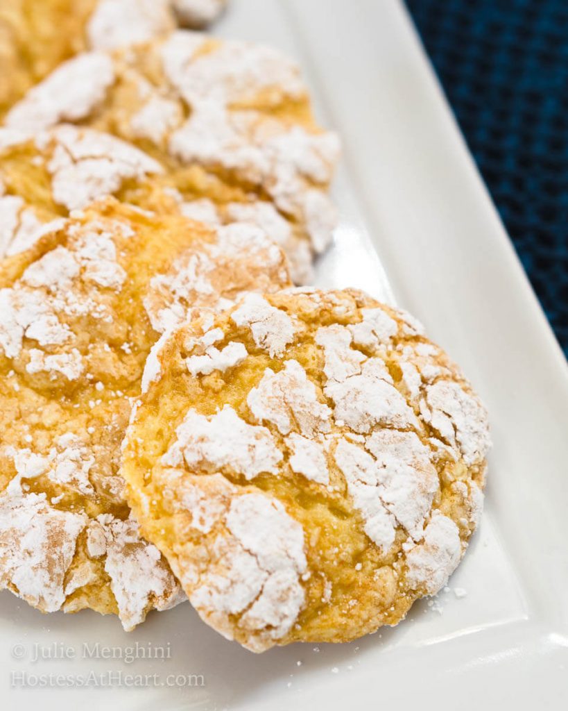 Front table view of yellow Lemon Snowflake cookies layered in a row on a white plate.