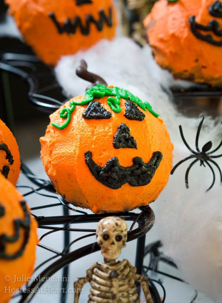 Chocolate Cake pumpkins surrounded by skeletons, spiders, and spider webs for Halloween.