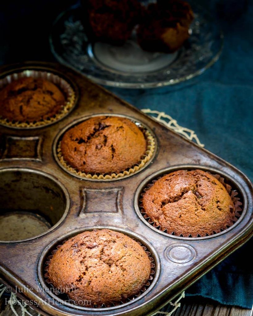 Corner of an antique pie tin filled with 4 Banana Chocolate Chip Espresso muffins.