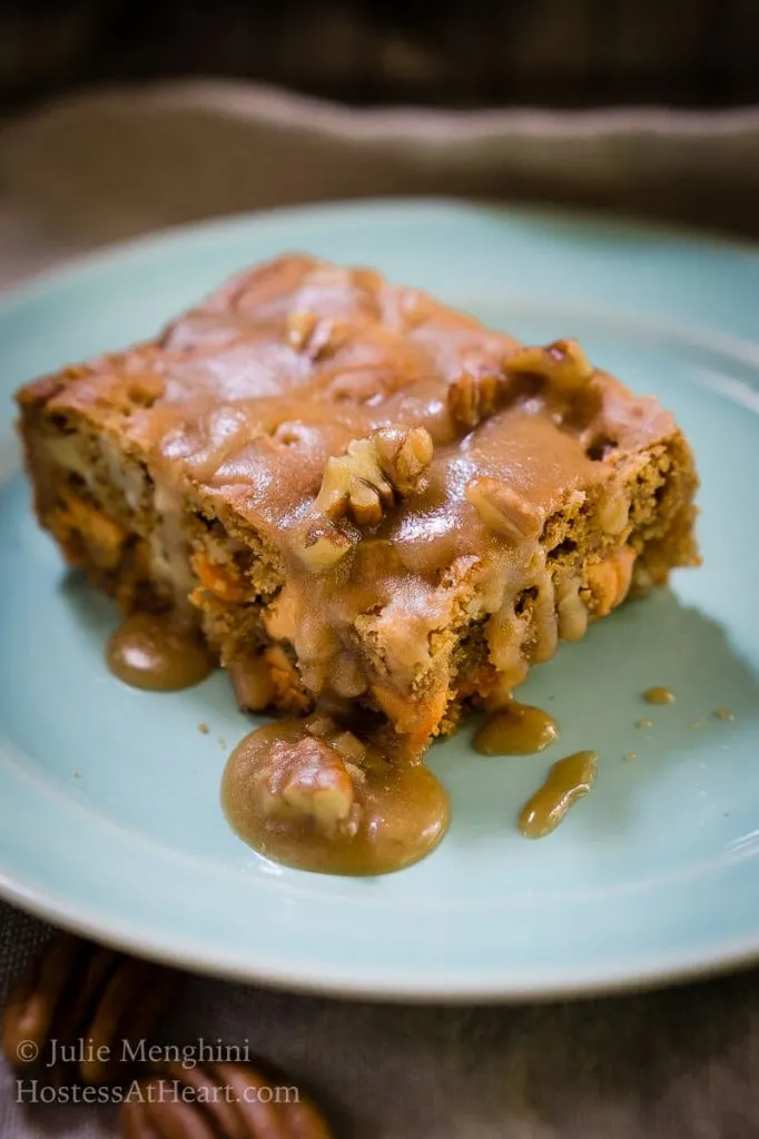 Butter Pecan Bar drizzled with a Brown Sugar Drizzle sitting on a blue plate.