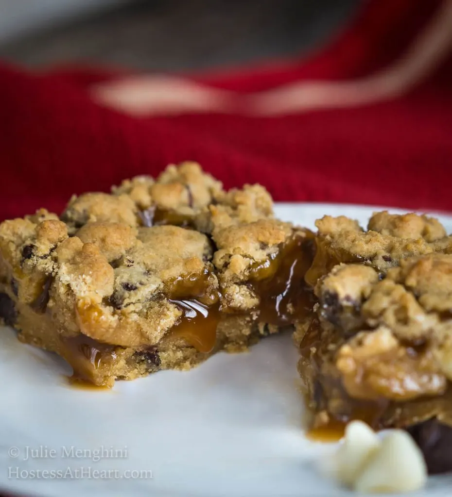 A bar ofl Chocolate Caramel Cookie sliced in half with caramel running onto a white plate. 