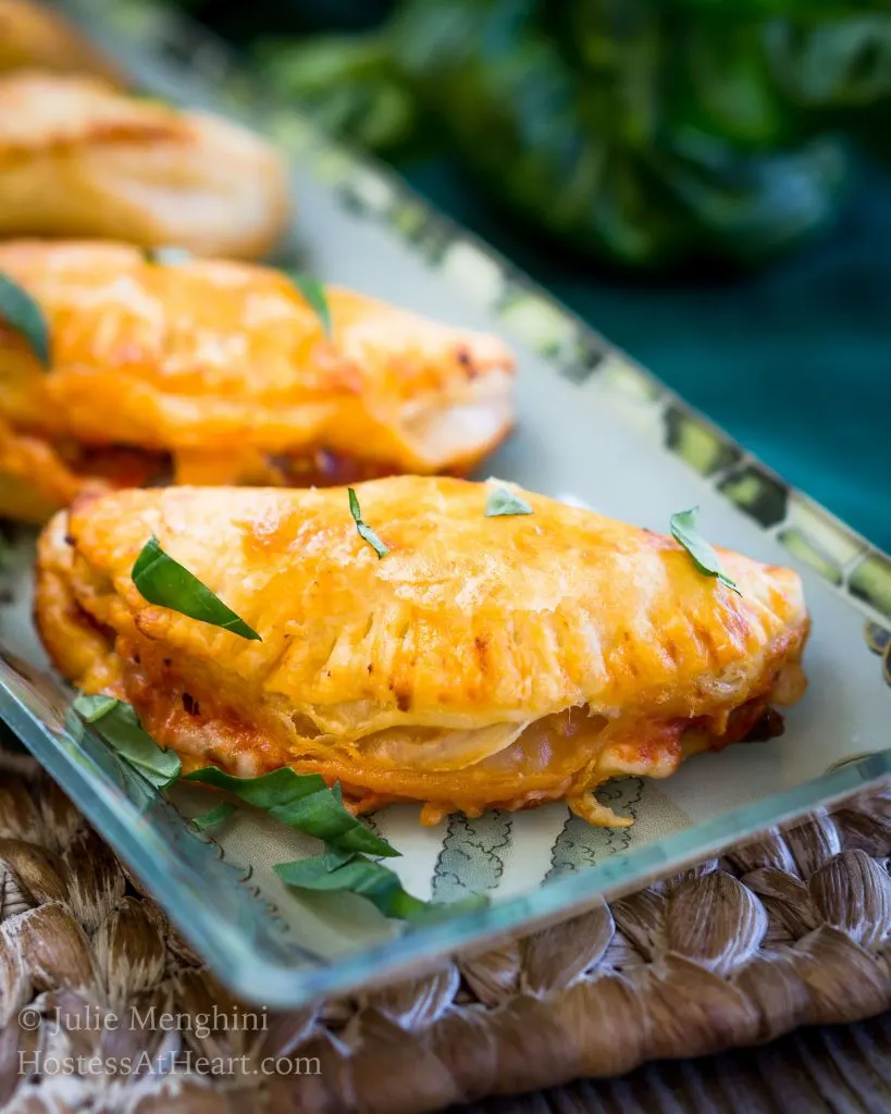 A close-up Cheese and Mushroom Empanadas sitting on a plate and garnished with fresh parsley.