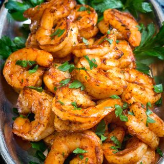 Top down view of a platter full of blackened shrimp garnished with parsley under a title banner.