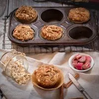 Rhubarb Oat Muffins in muffin tin and one muffin set in front with raw ingredients