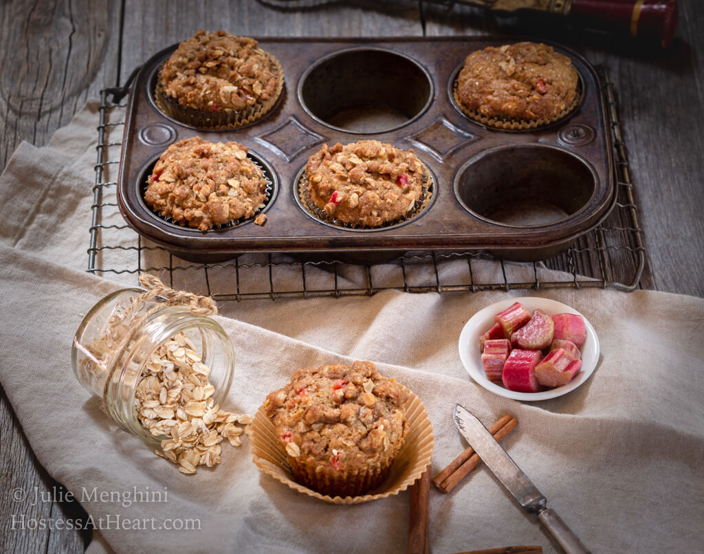 Rhubarb Oat Muffins in muffin tin and one muffin set in front with raw ingredients