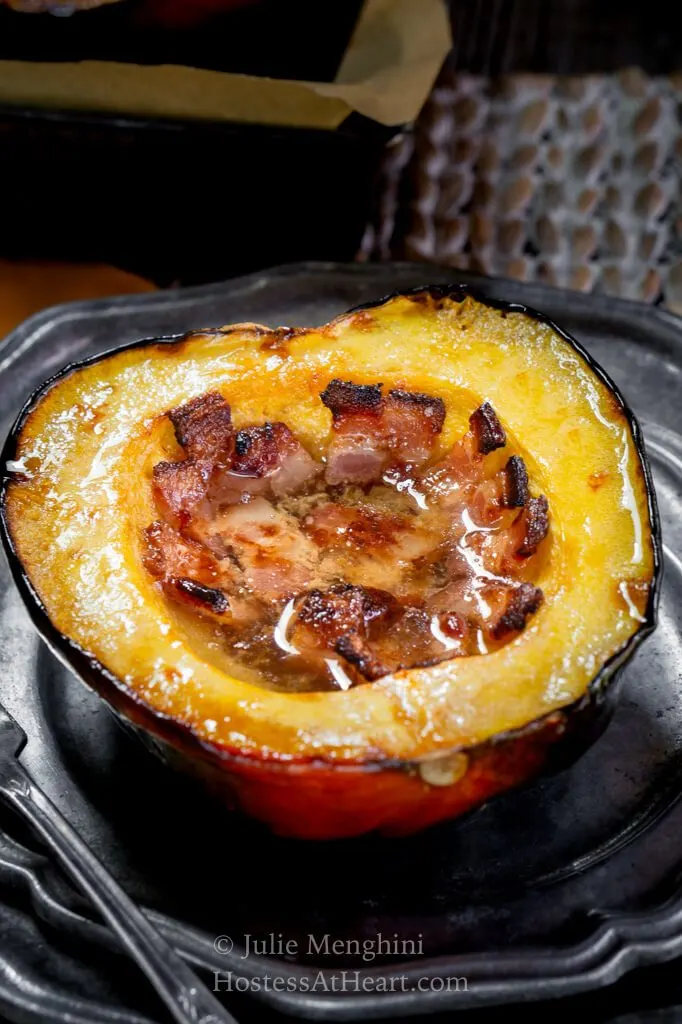 Acorn squash sliced in half and filled with bacon, butter and brown sugar on a metal plate
