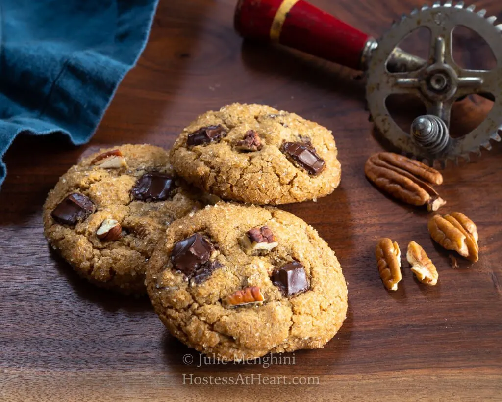 Three cookies in front of an antique egg beater.