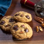 Three cookies in front of an antique egg beater.