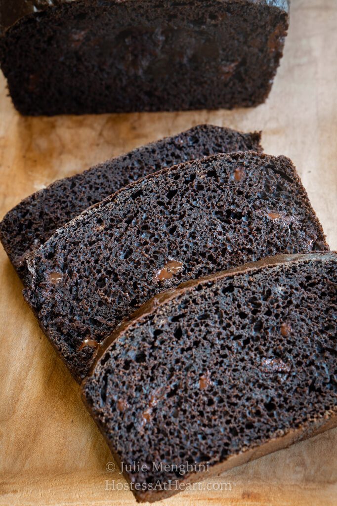 3 slices on dark chocolate banana bread on a wooden cutting board