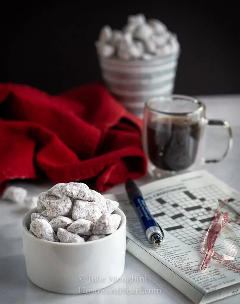 Close up with puppy chow in a bowl with a second serving in a pail